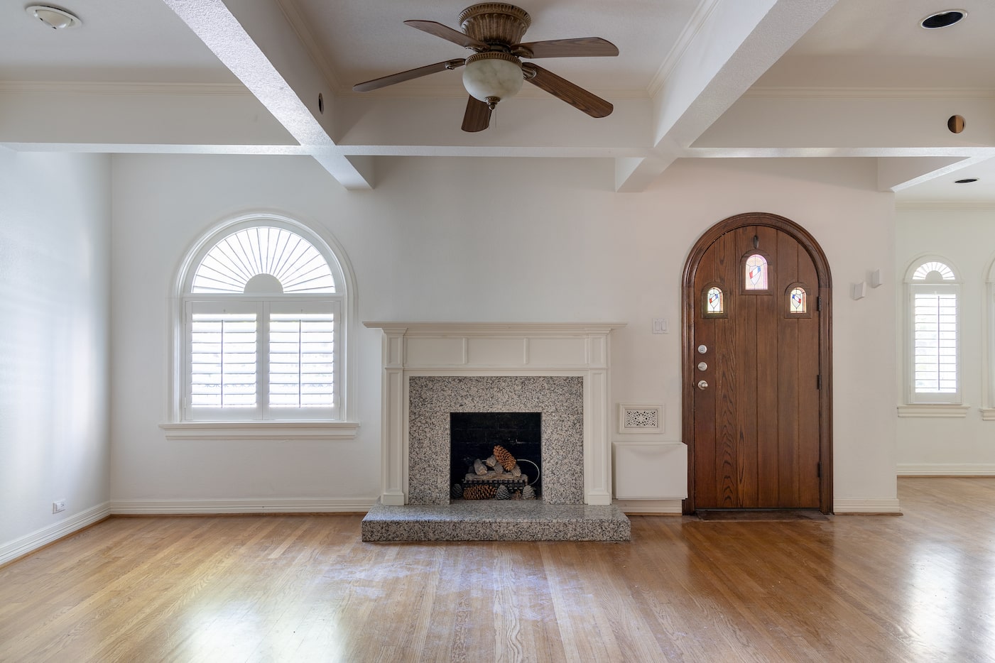 Living room interior with polished hardwood floors, white walls and gray fireplace