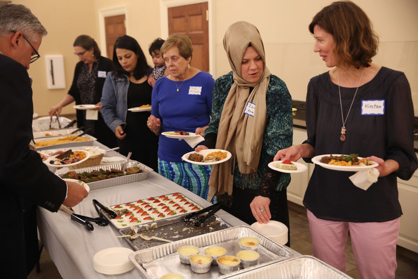 Kirsten Granberry (right) speaks with Zainab Aktepe while making their plates during an...