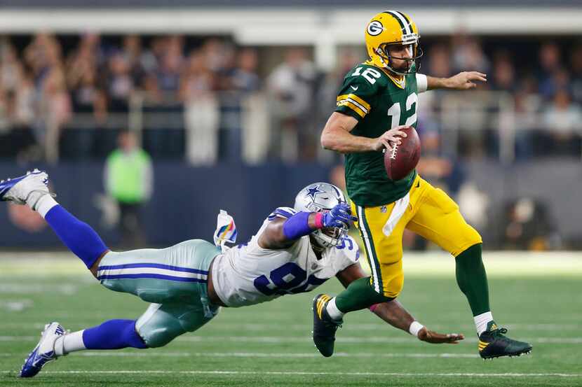 Green Bay Packers quarterback Aaron Rodgers escapes the grasp of Dallas Cowboys defensive...
