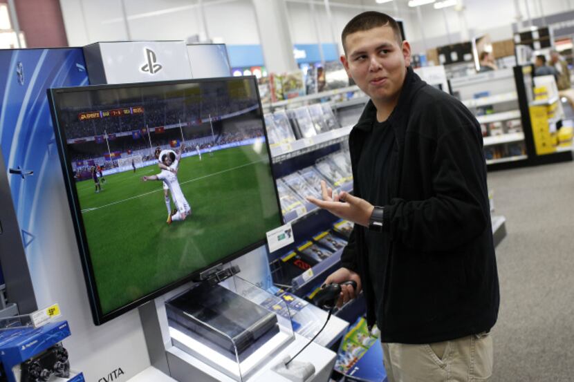 Max Garcia plays FIFA 2014 on the new Sony PlayStation 4 at Best Buy in Dallas.