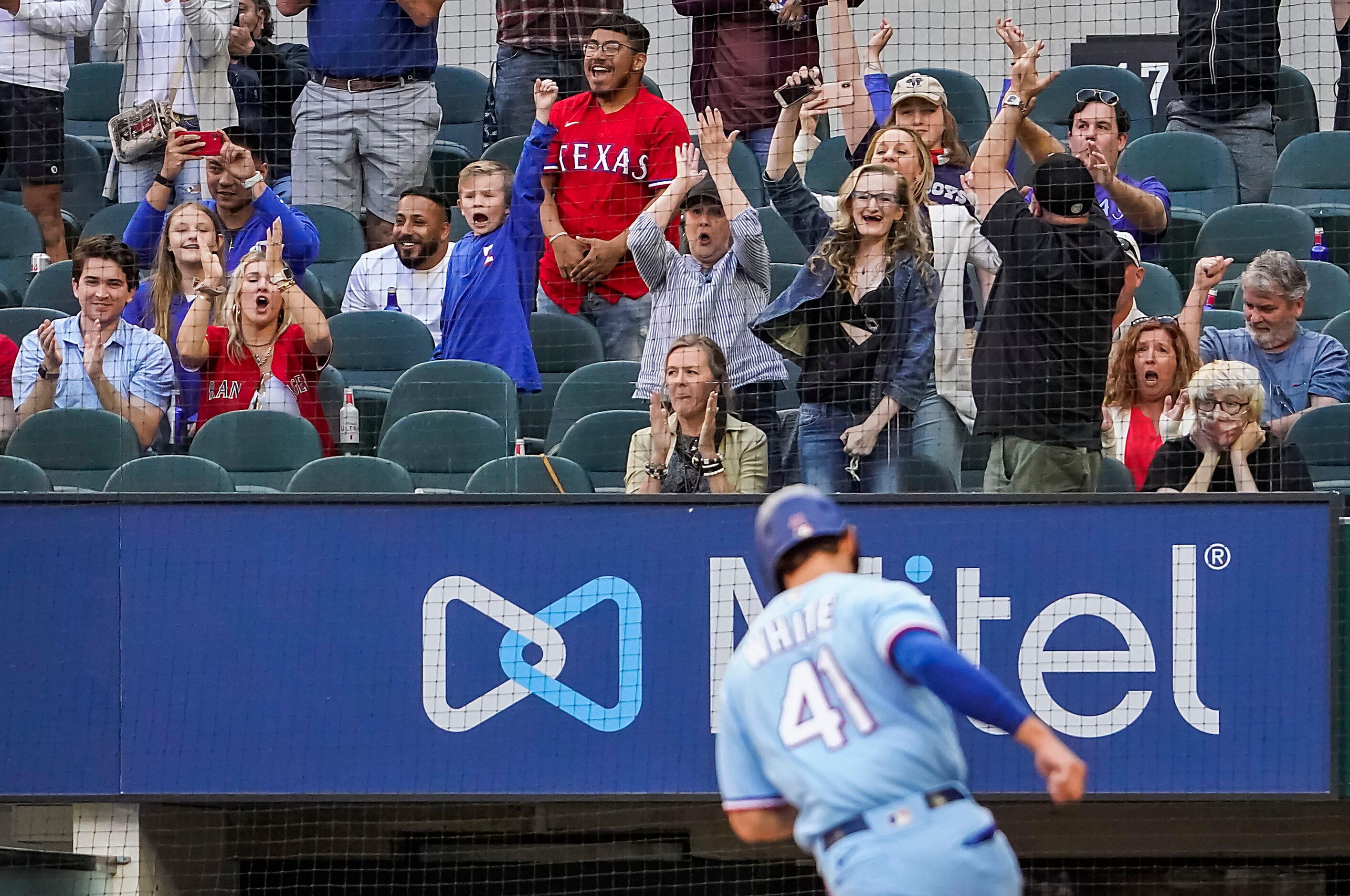 Texas Rangers fans cheer as outfielder Eli White scores from third base on a walk-off single...