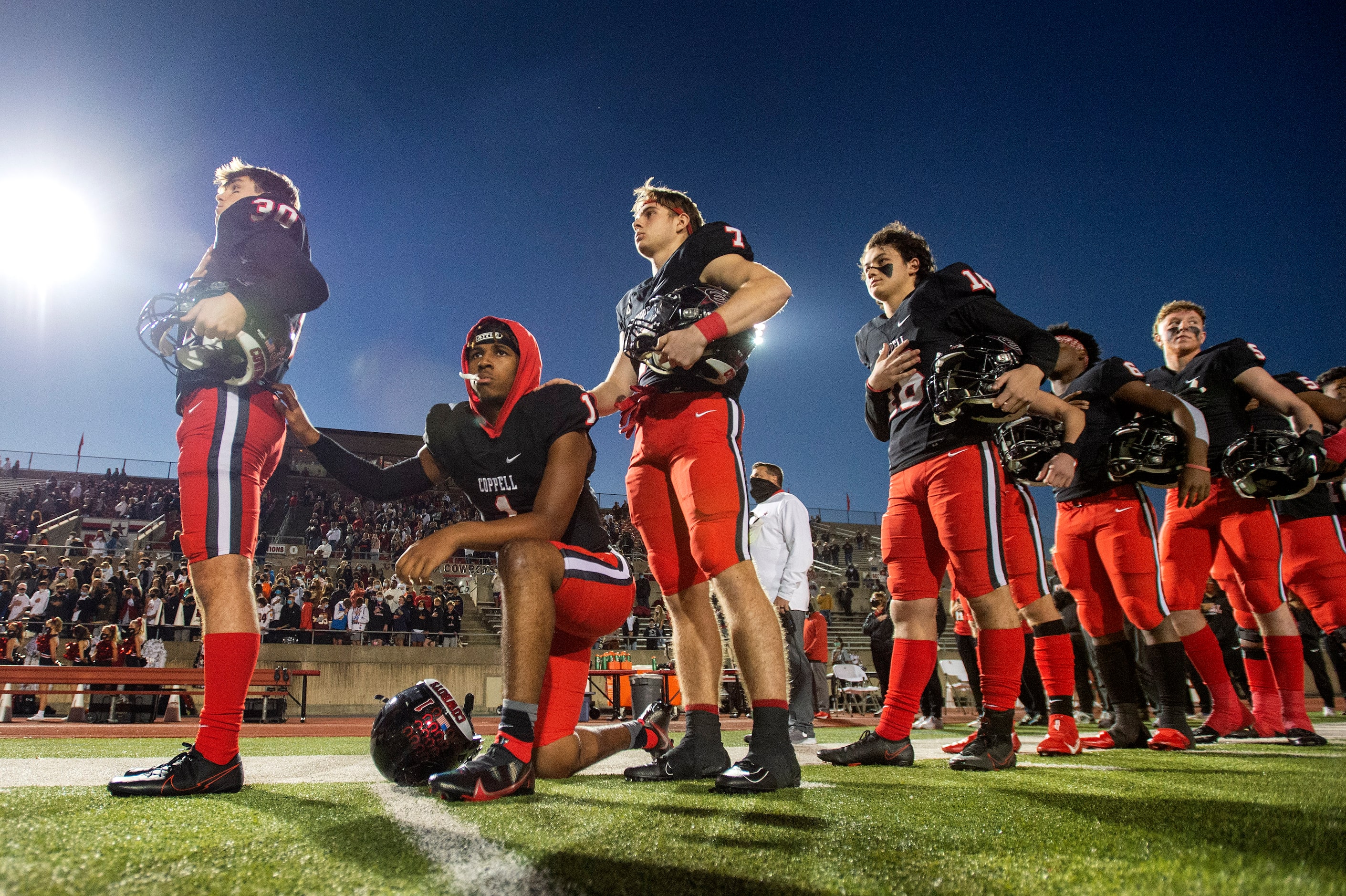 Coppell senior wide receiver KJ Liggins (1) takes a knee during the playing of the national...