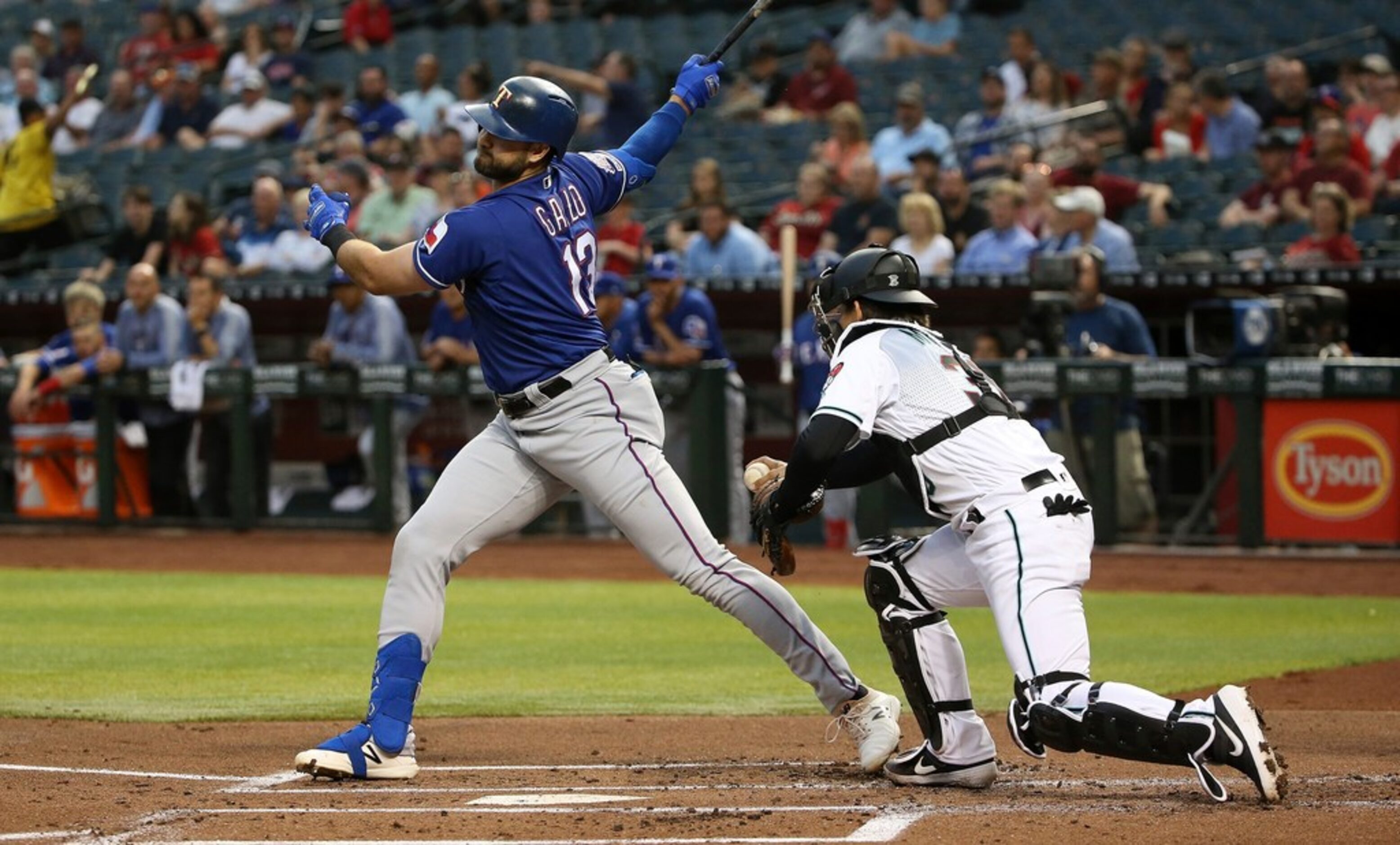 After swinging on a third strike, Texas Rangers' Joey Gallo, left, is tagged out by Arizona...