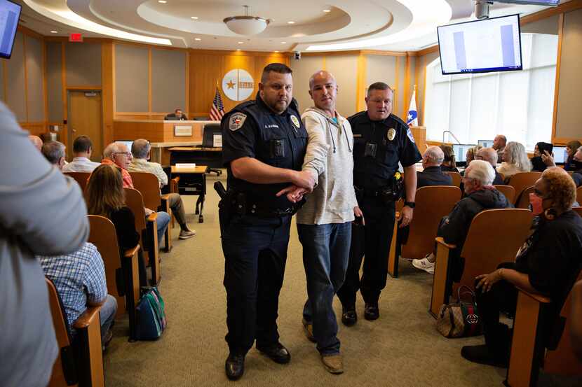 Joshua Murray is escorted out of the Collin County Commissioners Court meeting by police...