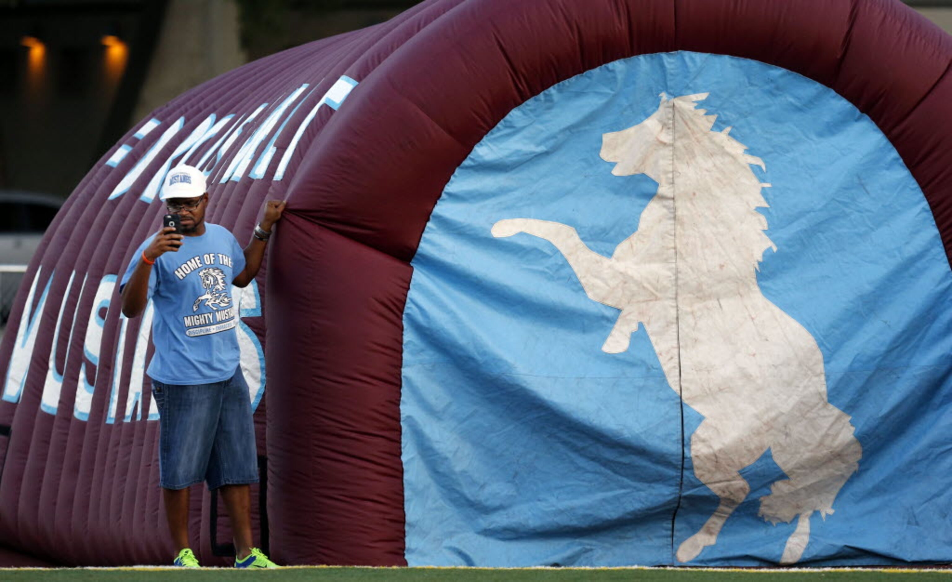 (TXHSFB) A Roosevelt High booster takes a picture with his smart phone, while holing down...