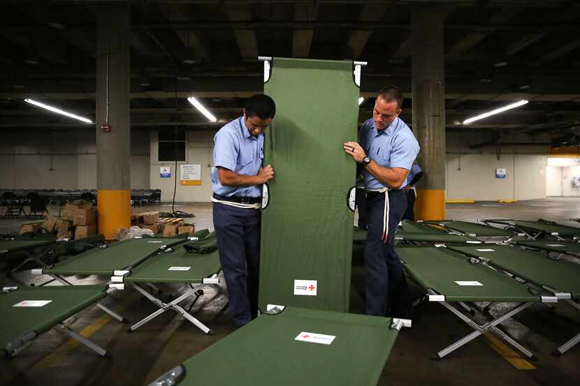 Dallas Fire-Rescue recruits Marco Huerta (left) and Nathan Johnson help set up beds to house...