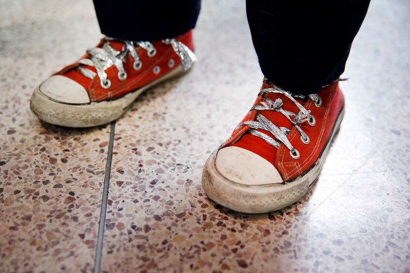 An immigrant child fleeing Central America uses makeshift shoelaces crafted from aluminum...