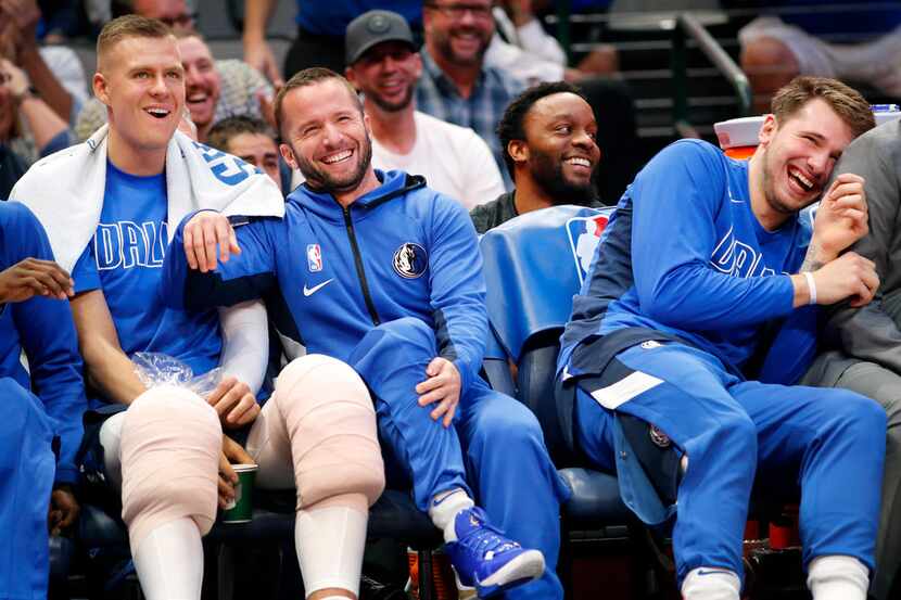 Dallas Mavericks guard J.J. Barea (center) laughs with teammates Kristaps Porzingis (left)...