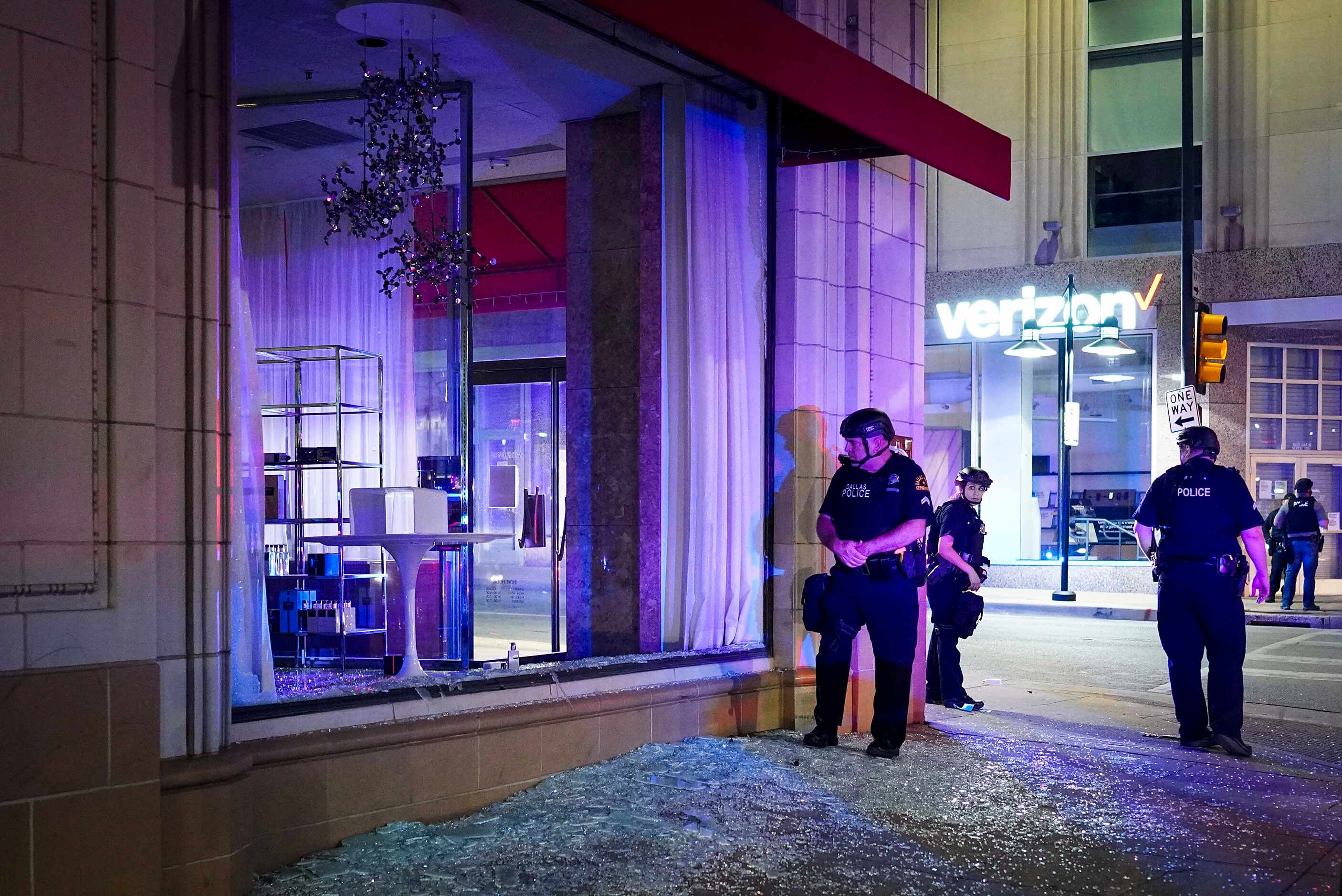 Dallas police stand guard amidst broken glass after windows were smashed at the Nieman...