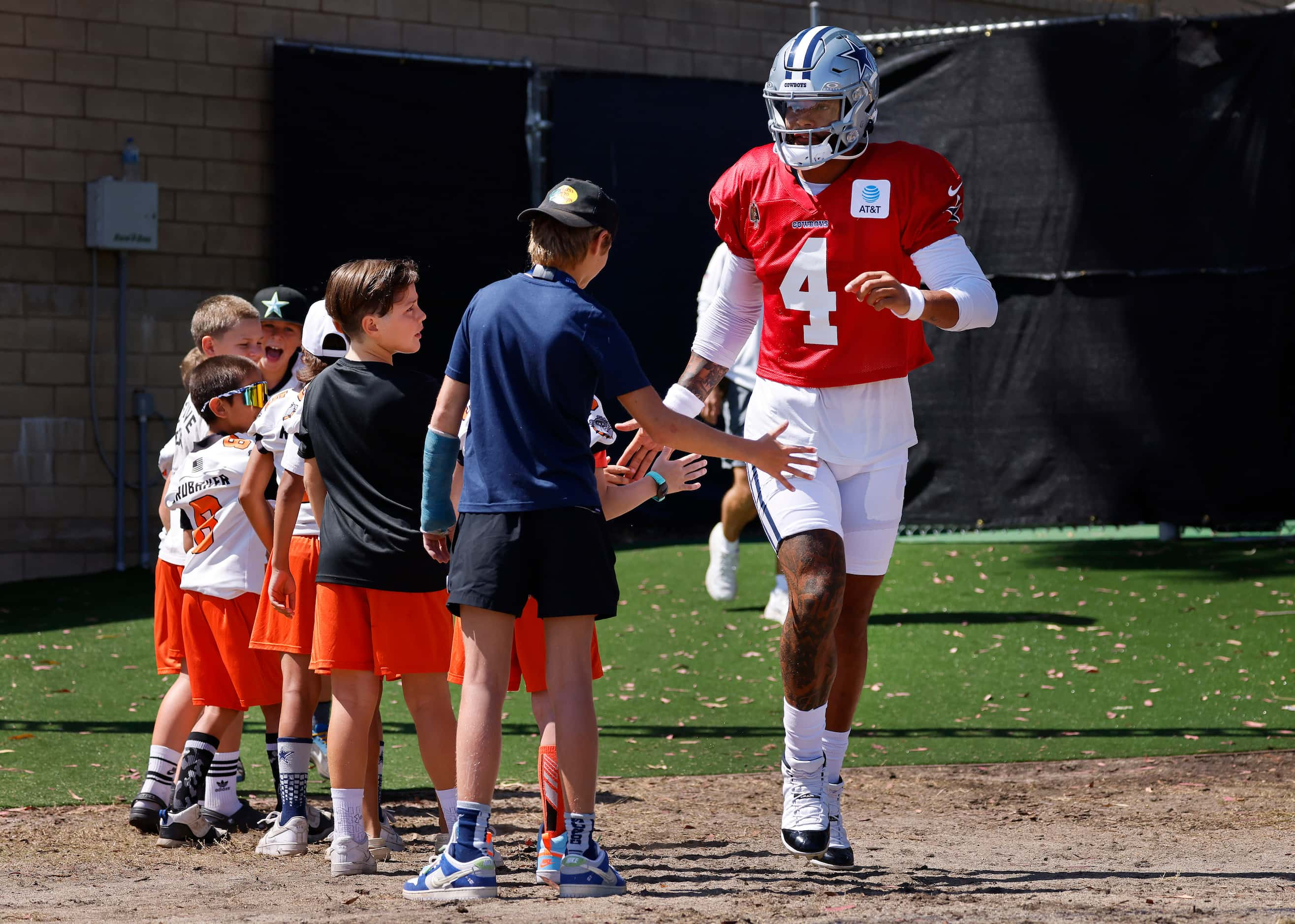 Dallas Cowboys quarterback Dak Prescott (4) slaps hands with Simi Valley Bulldogs youth...