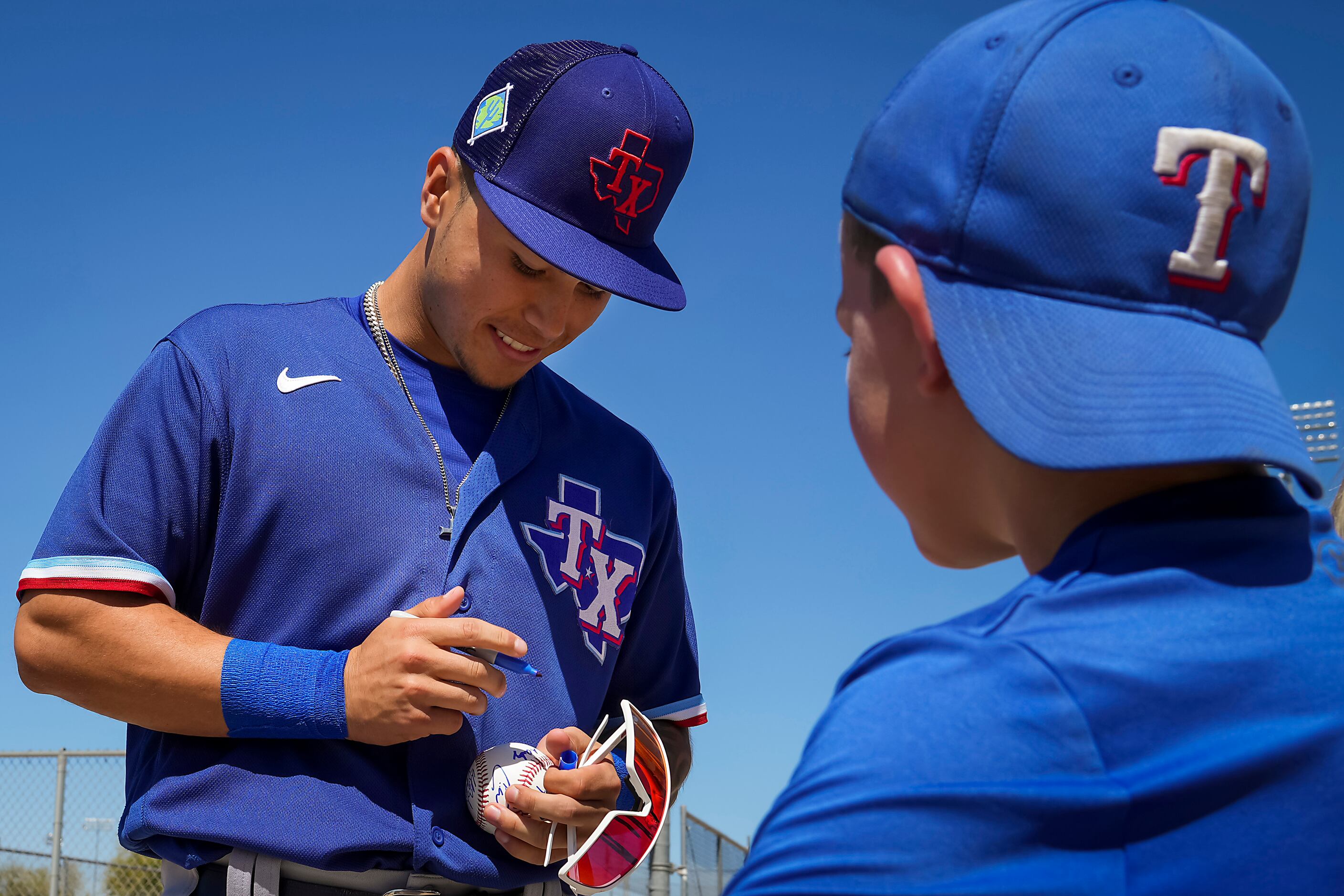 Texas Rangers minor league catcher Cody Freeman autographs a baseball for a young fan during...