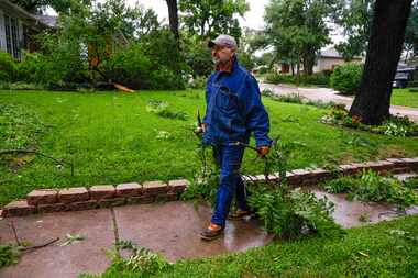 Glenn Kasperian clears branches from his yard and the street outside his home after a...