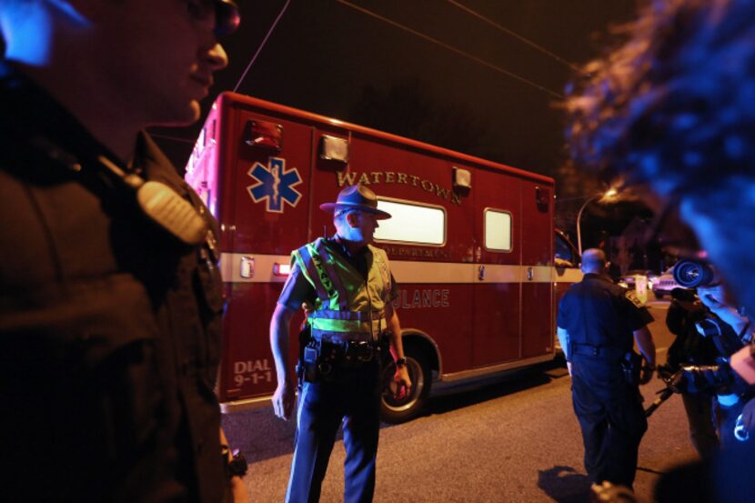 Police officers stand by as an ambulance passes after the successful operation to capture...