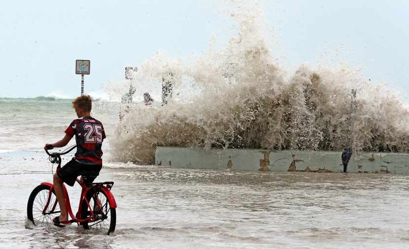 A Key West resident watches Saturday as waves crash onto a seawall in Key West, Fla.. 