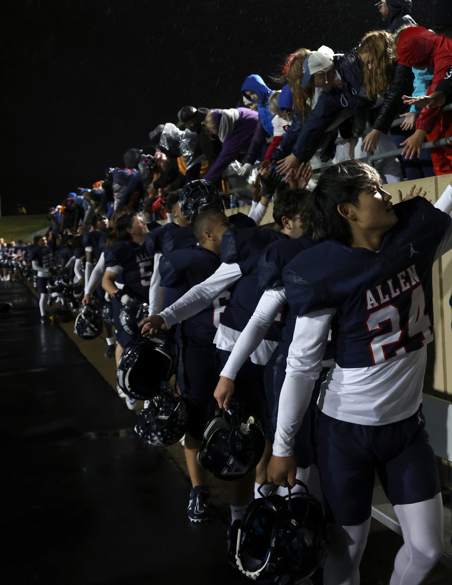 Allen players go through a reception line as fans in the stands congratulate them on their...