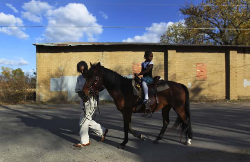David Shanks leads his granddaughter, Derrionna "DeeDee" Shanks, 6, atop his horse Luther...