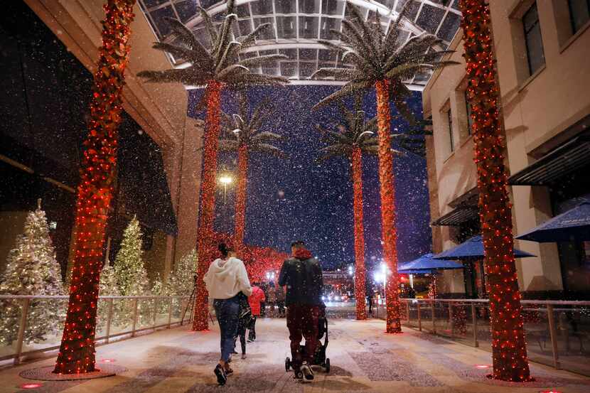 Visitantes de Galleria Dallas caminan bajo la nieve artificial que cae cada día en la...