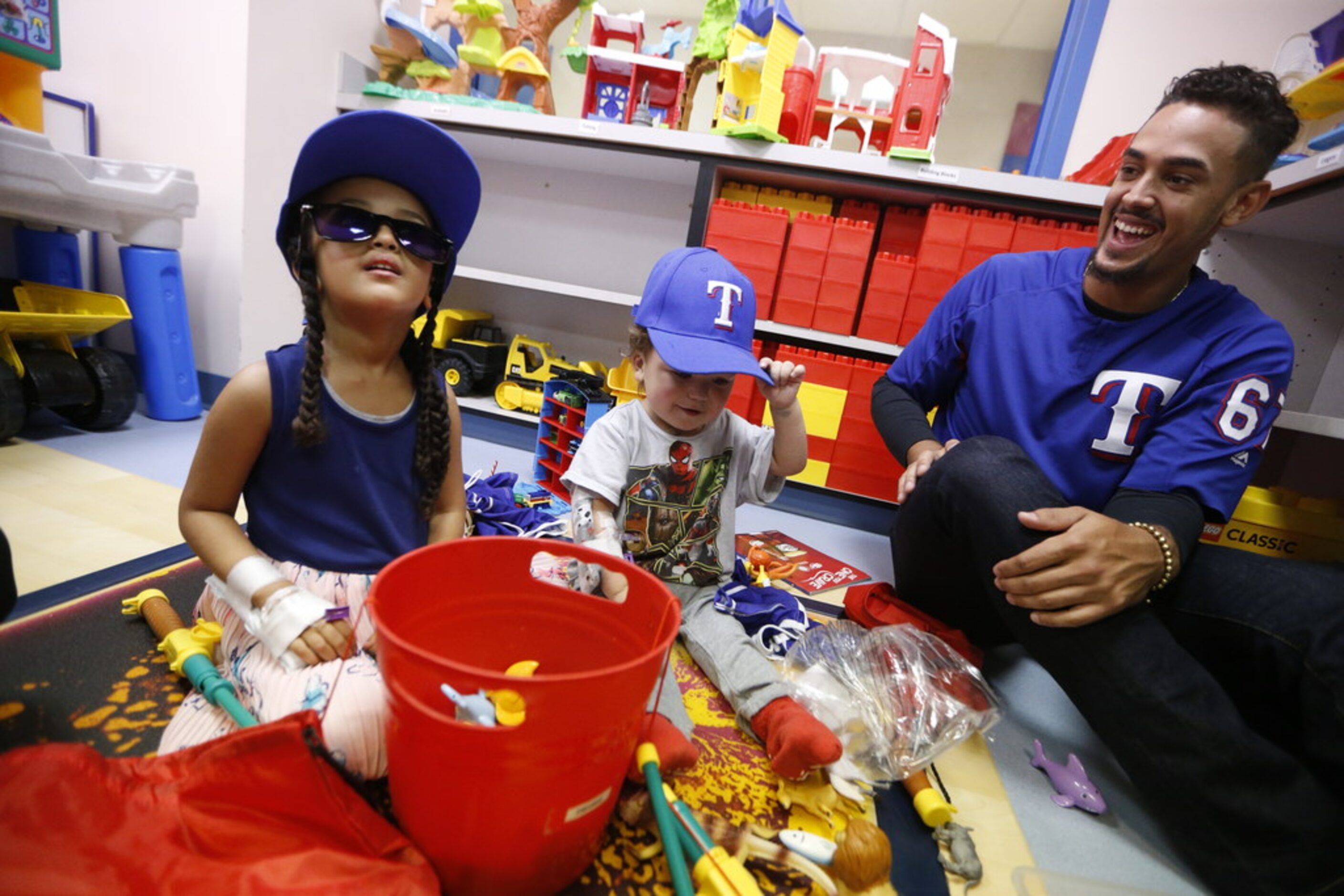 Texas Rangers' Ronald Guzman (right) gives Haleluya Shaga, 4, (left) and Elliott Wyche, 3,...