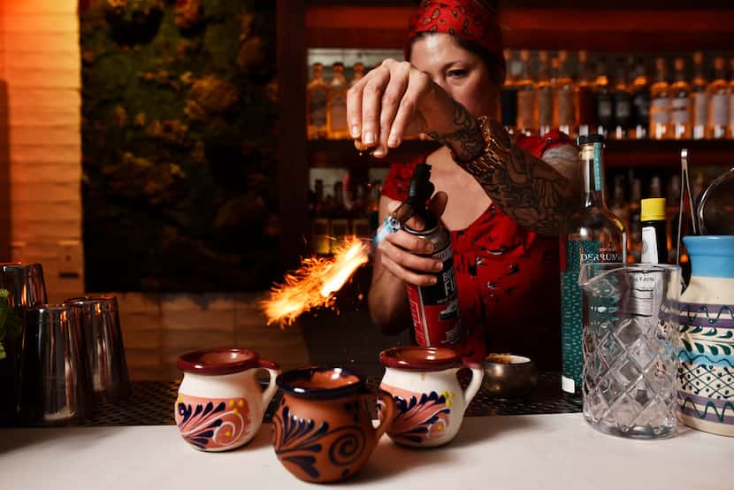 La Viuda Negra bar manager Candice Ruibal uses a blowtorch to toast cinnamon as she...