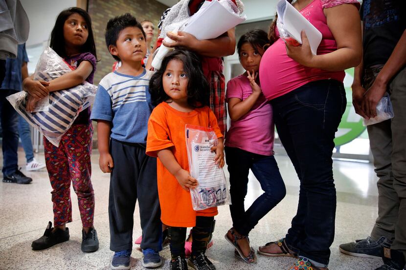 Four Guatemalan children and their mothers wait after being processed by the U.S. Border...