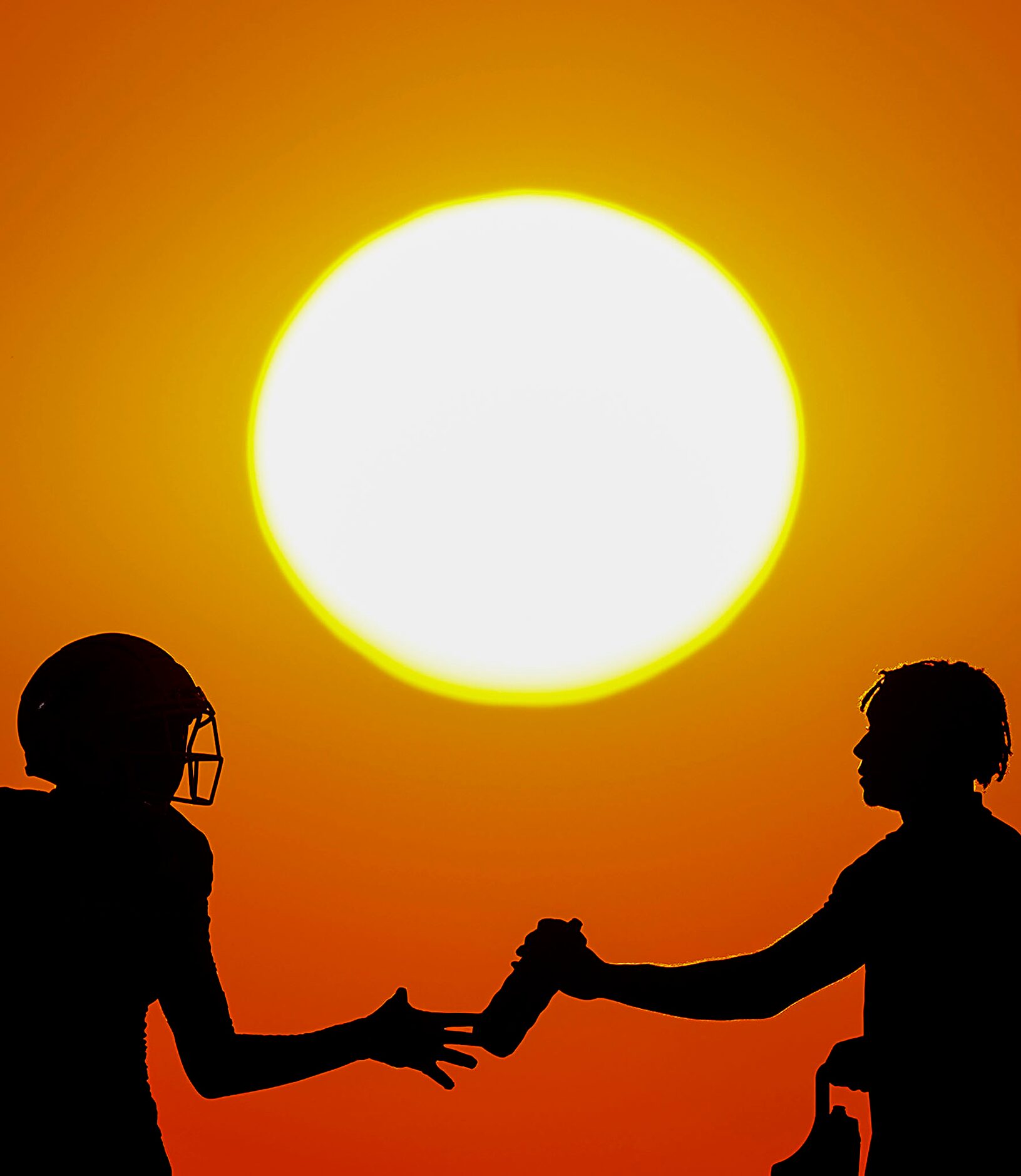 A Wilmer-Hutchins player gets a drink of water as the sun sets during the first half of a...