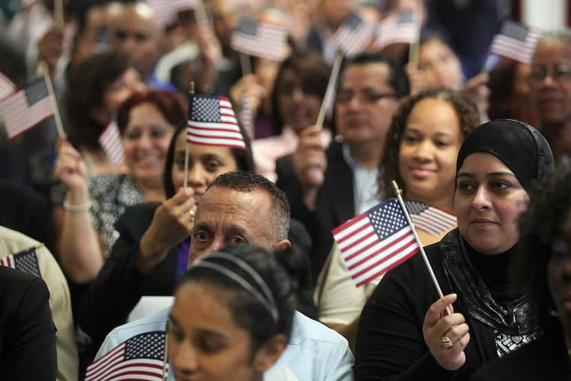 NEW YORK, NY - JULY 02:  People wave American flags at a naturalization ceremony in downtown...