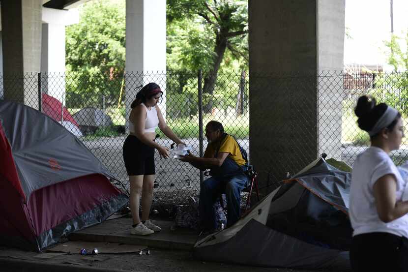 Volunteer Olivia Najera-Garcia hands out bottled water in under-freeway encampments for Feed...