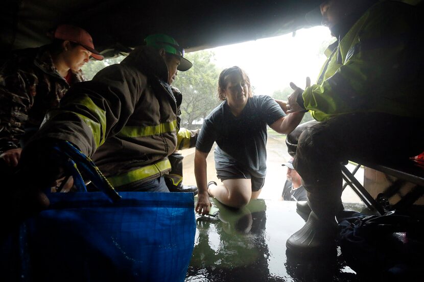 Volunteers Jay Garcia (second from left) and Aaron Crump (right) help Sheila Penton crawl...