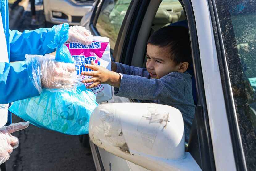 Adolfo Chavarria, 3, receives food aid from volunteer Rachel Harper, 15, at Ledbetter Eagle...