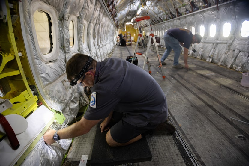 Aircraft maintenance technician Chris Streeter secures electrical wires during a routine...