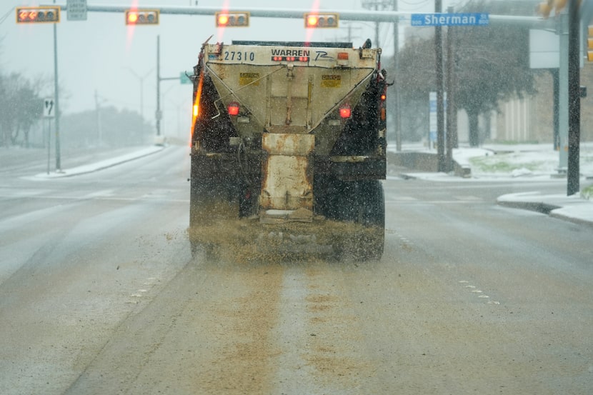 A truck treats a road for better driving conditions as snow falls Thursday, Jan. 9, 2025, in...