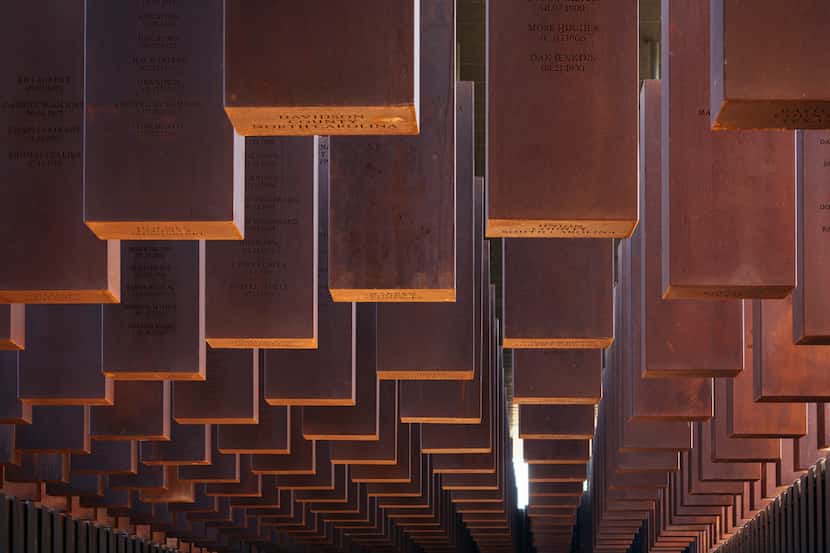 Some of the 800 weathered steel columns, each one etched with the names of lynching victims,...