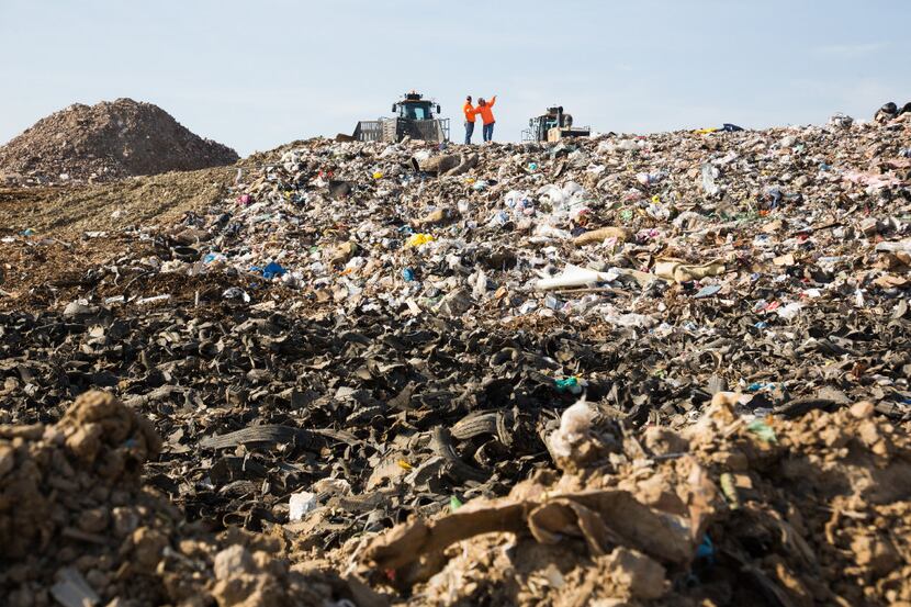 The two workers stand on top of a hill of garbage in landfill section at ECO-W.E.R.C.S....