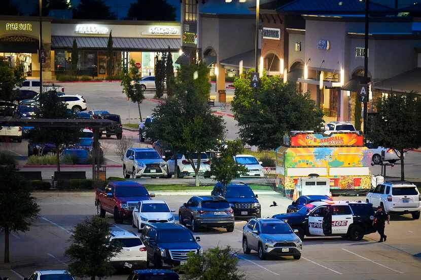Allen police work inside the mall parking lot a day after a mass shooting at Allen Premium...