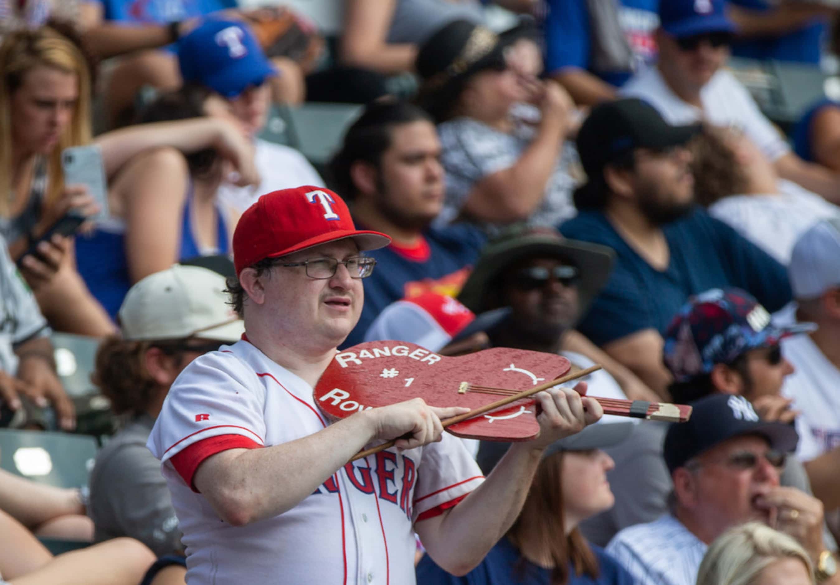 A fan plays a makeshift violin while singing along with "Deep in the Heart of Texas" during...