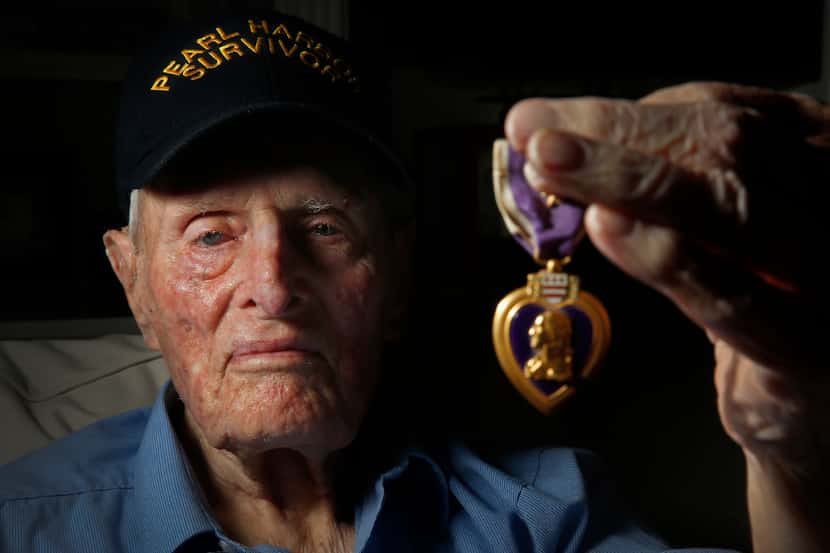 Pearl Harbor survivor John E. Lowe holds his Purple Heart at his son's house in Arlington....