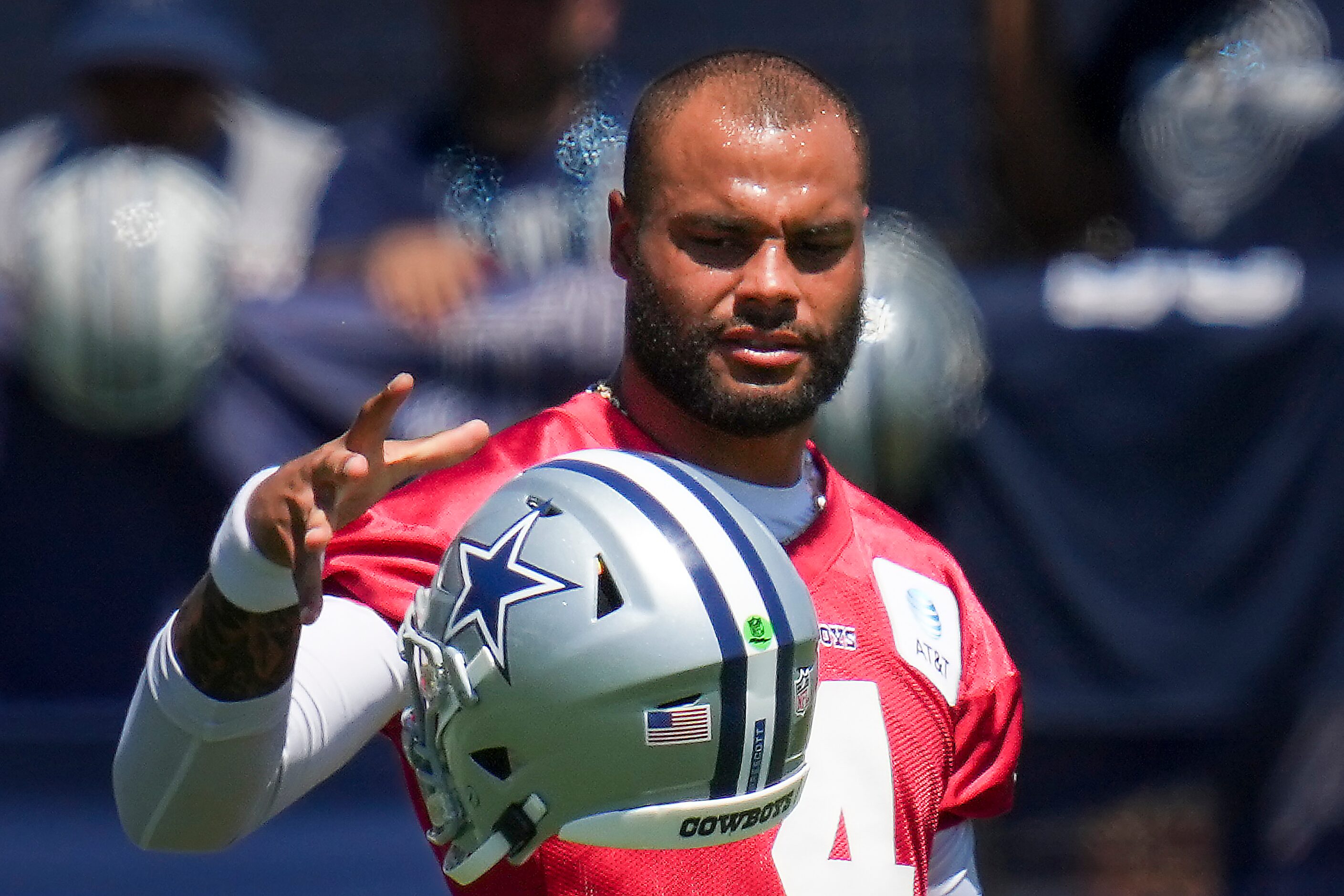 Dallas Cowboys quarterback Dak Prescott juggles his helmet during a training camp practice...