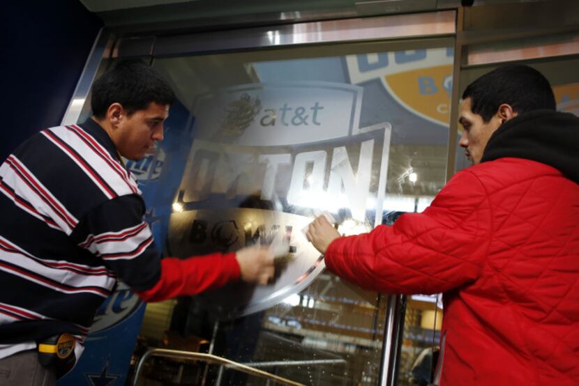 Mario Chavez (left) and Fidel de Avila of EH Teasley Inc. mount a decal on to a door...