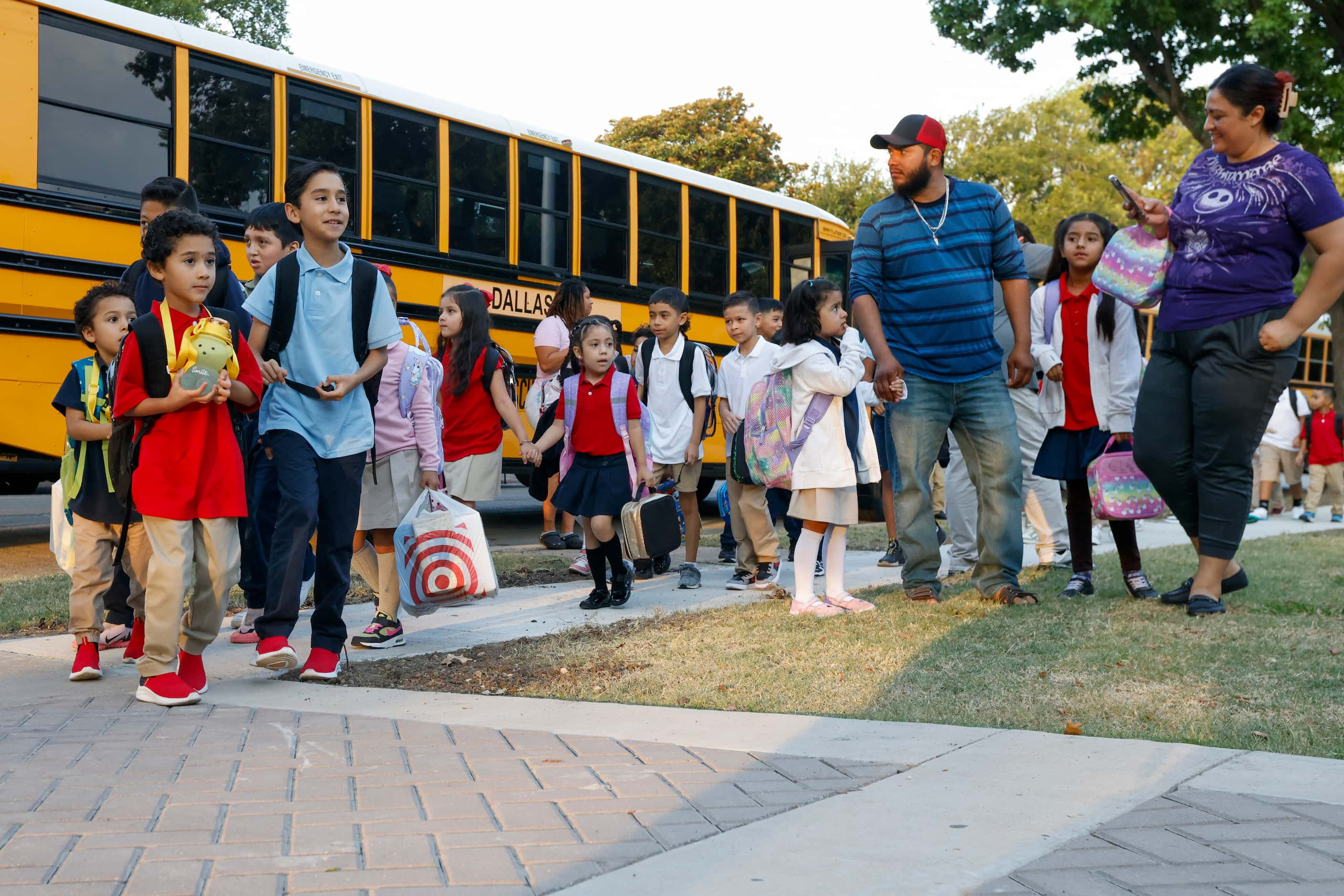 Family members watch as students walk to John J. Pershing Elementary School for the first...