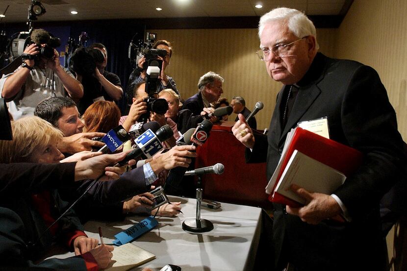 Cardinal Bernard Law (right) departs a news conference during the second day of the U.S....