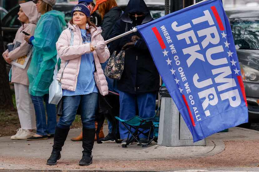 Una mujer ondea una bandera con los nombres de JFK Jr y Trump. No hay nada que pueda...