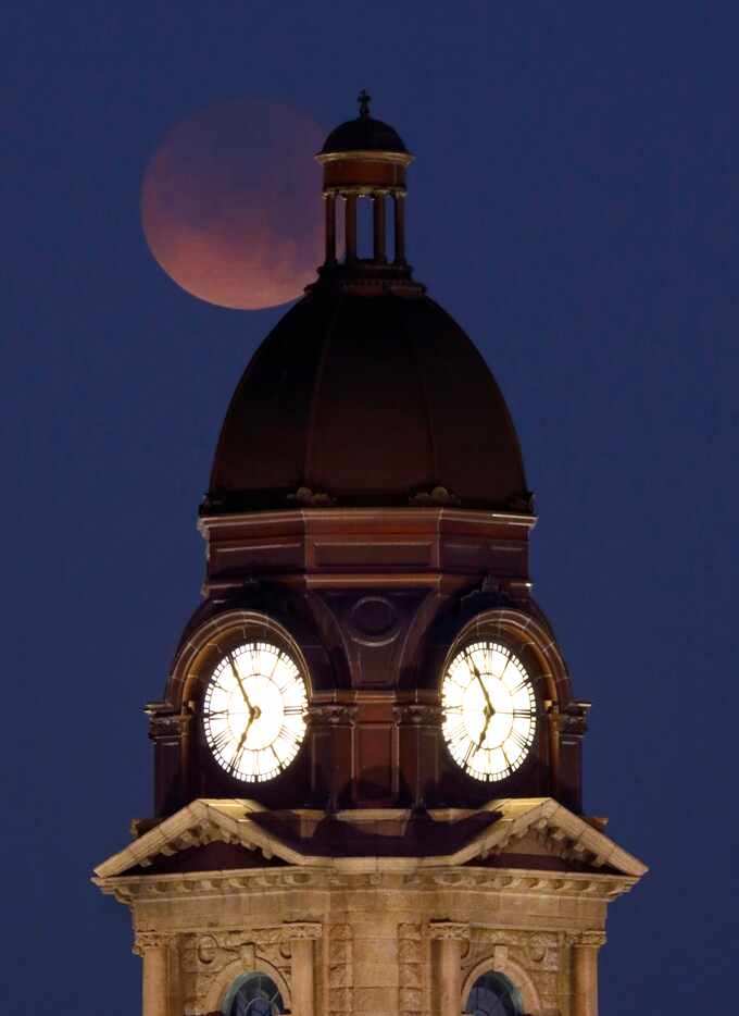 A partial Super Blue Blood Moon begins to set over the old Tarrant County Courthouse in...
