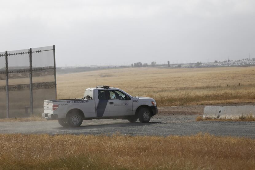 A Customs and Border Protection truck patrols the border fence east of Otay Mesa in San...