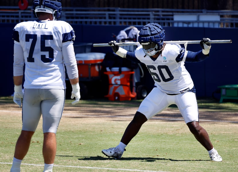 Dallas Cowboys tackle Tyler Guyton (60)  uses a pipe to run through drills before a training...