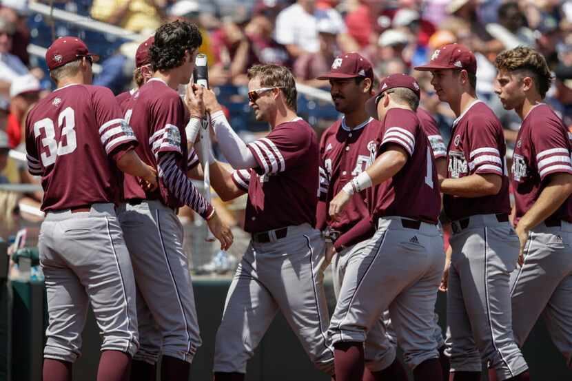 Texas A&M's Blake Kopetsky, center, is greeted at the dugout after scoring a run against...
