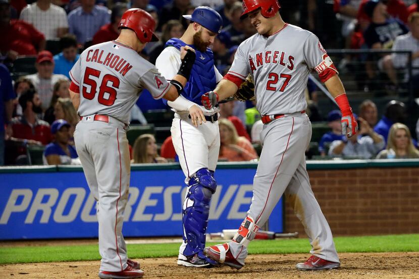 Los Angeles Angels' Kole Calhoun (56) and Mike Trout (27) celebrate a two-run home run by...