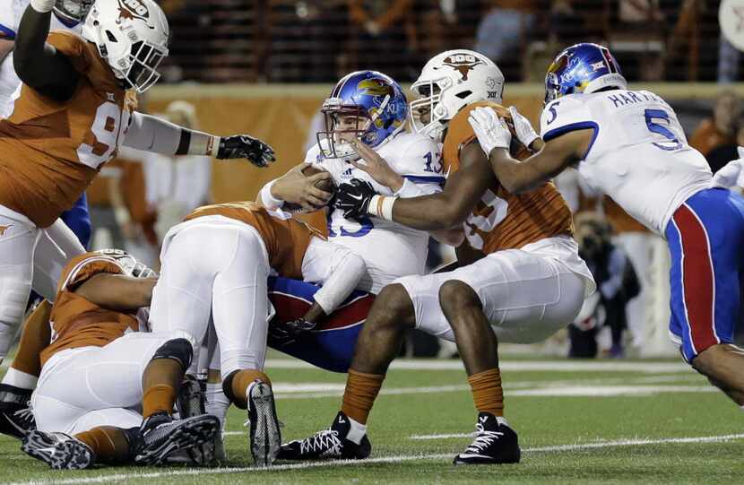 Kansas quarterback Ryan Willis (13) is stopped by Texas defenders during the first half of...