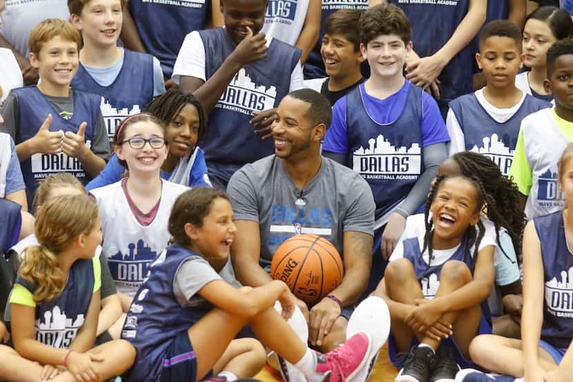 Dallas Mavericks point guard Devin Harris, center , laughs with they pose in a group photo...