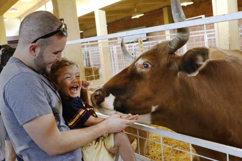 William Peter, left, holds his son, Maddox, 2, at the petting zoo at the State Fair of Texas...