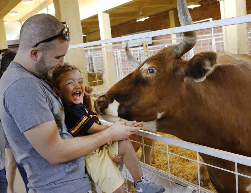 William Peter, left, holds his son, Maddox, 2, at the petting zoo at the State Fair of Texas...